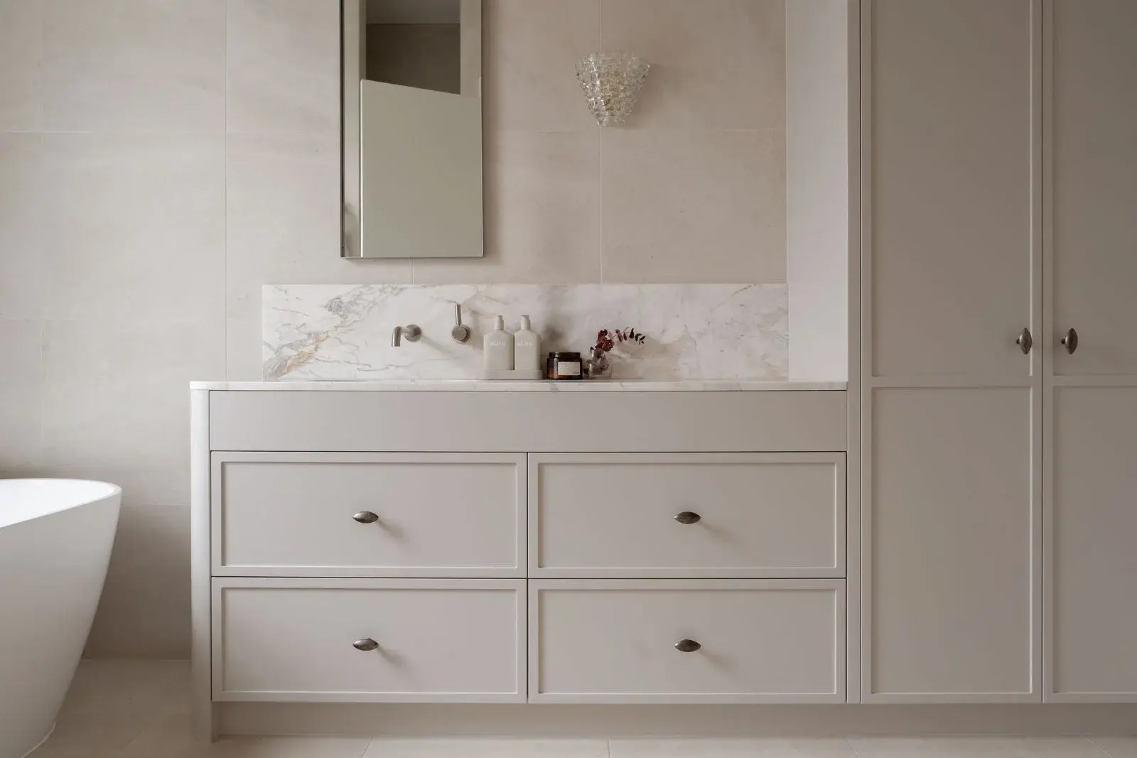 Vanity with marble splashback and sconce lighting