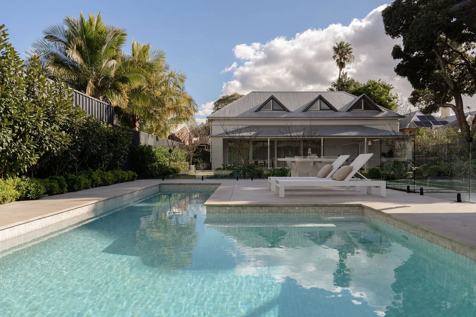 Heated magnesium pool with loungers beneath the triple-gabled roofline